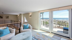 Ein geräumiges Wohnzimmer mit einem großen Schiebeglasfenster, das auf einen Balkon mit Meerblick führt.