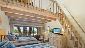 Ein Schlafzimmer mit zwei Betten, einem Fernseher, einem Schminktisch und einer Treppe.