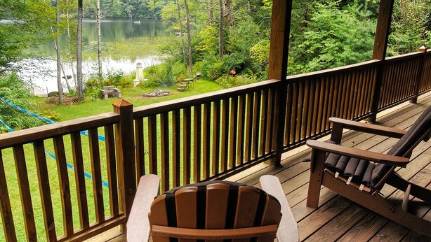 Una terraza de madera con vistas a un lago y follaje circundante.