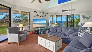 A modern living room with a large TV, comfortable seating, and a view of the ocean. - Sale!! Gorgeous 3BR 2BA Villa in Wailea, With Ocean, Golf and Sunset Views (Kihei)