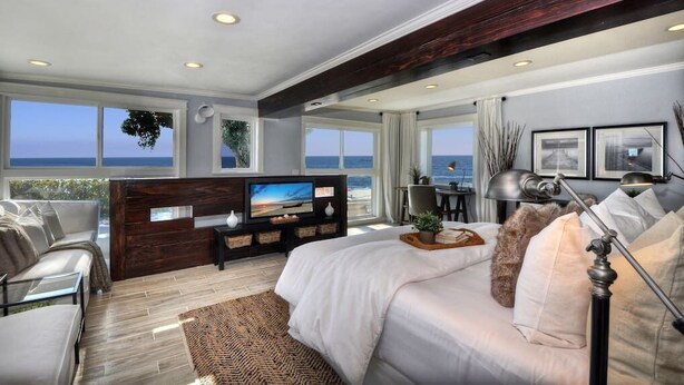 A modern bedroom with a large bed, a TV, and a view of the ocean. - Villa Laguna -- ocean views, walkable, and new (Laguna Beach)
