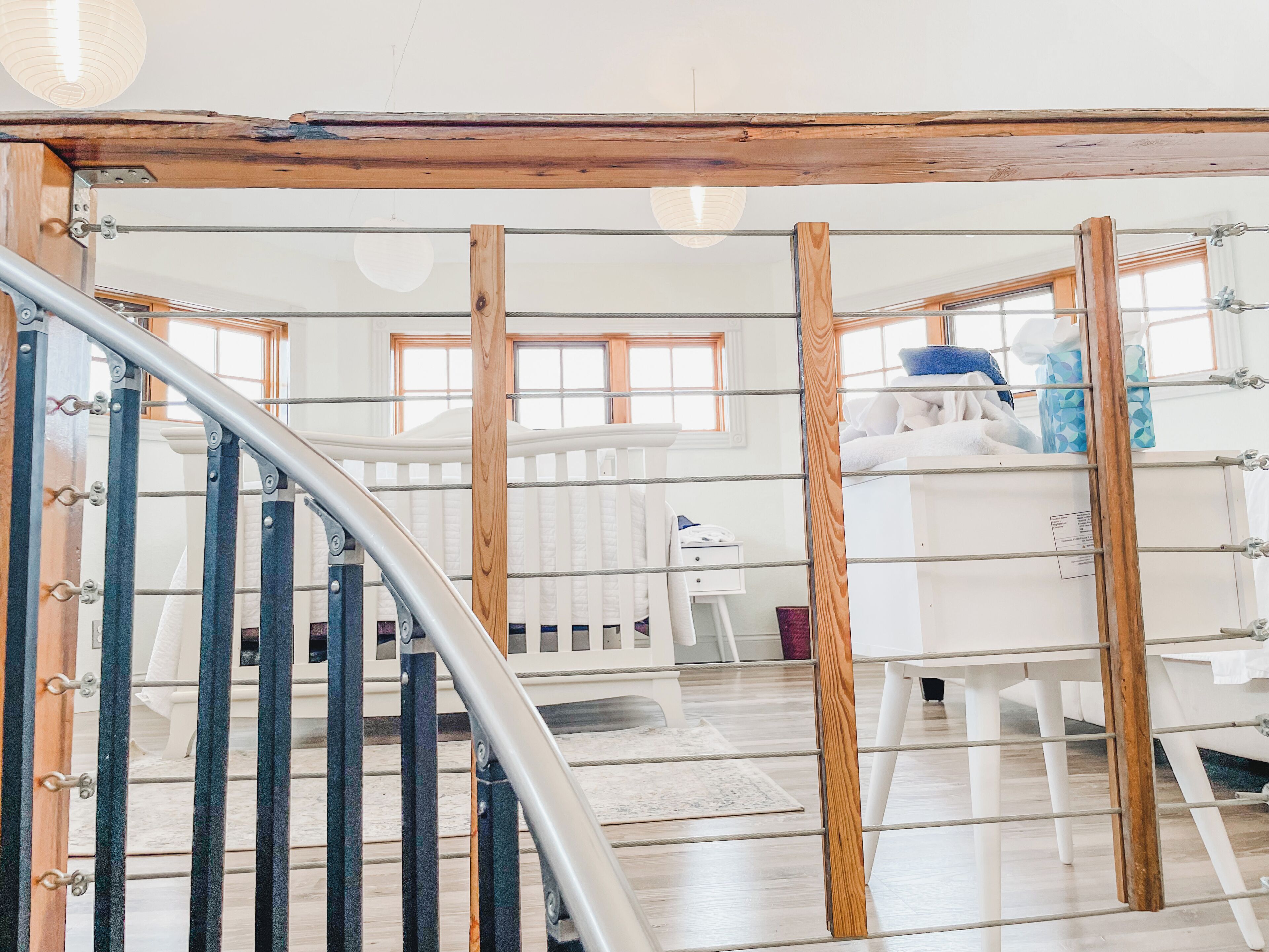 Un intérieur moderne avec un escalier en bois, des meubles blancs et une vue sur un espace cuisine.
