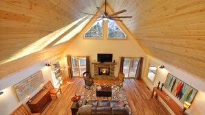 Una sala de estar estilo loft acogedora, con chimenea, pisos de madera y un ventanal grande.