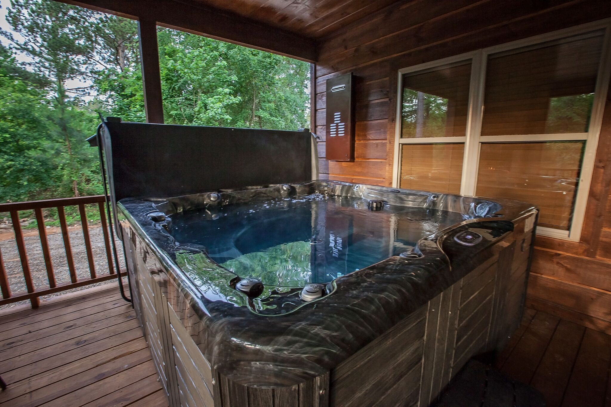 A hot tub on a wooden deck with a view of trees.