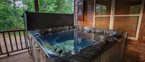 A hot tub on a wooden deck with a view of trees.