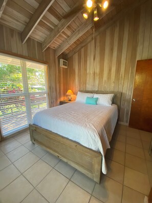 Cozy bedroom with a wooden bed frame, sloped ceiling, and a window with blinds.