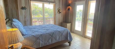 Een slaapkamer met een bed, nachtkastje, lamp en plafondventilator.