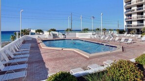 Un espace piscine avec des chaises longues et vue sur l’océan.