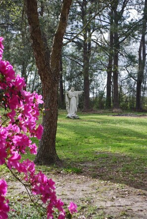 Una estatua en un parque con árboles y flores rosadas.