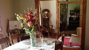 Un comedor con una mesa redonda cubierta por un mantel floral, rodeado de sillas de madera.
