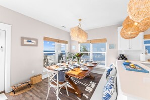 Une cuisine moderne dotée d’un grand îlot central, de planchers en bois et offrant une vue sur l’océan.