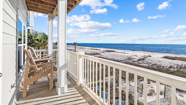 Une terrasse en bois avec une balustrade donnant sur une plage.