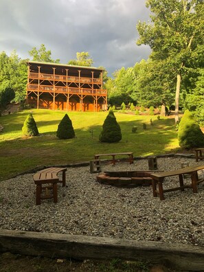 A wooden cabin with a balcony, surrounded by a well-maintained lawn and trimmed trees. - Buck Mountain Getaway - Stunning views, hot tub, fireplace. Nearby Boone. (Purlear)