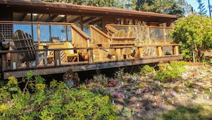 A wooden deck with chairs and a railing overlooking a garden with various plants. - Family Friendly Home on 20 Acre Farm (Caspar)