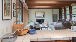 A spacious living area with a fireplace, comfortable seating, and a kitchen area with a tiled backsplash. - Family Friendly Home on 20 Acre Farm (Caspar)