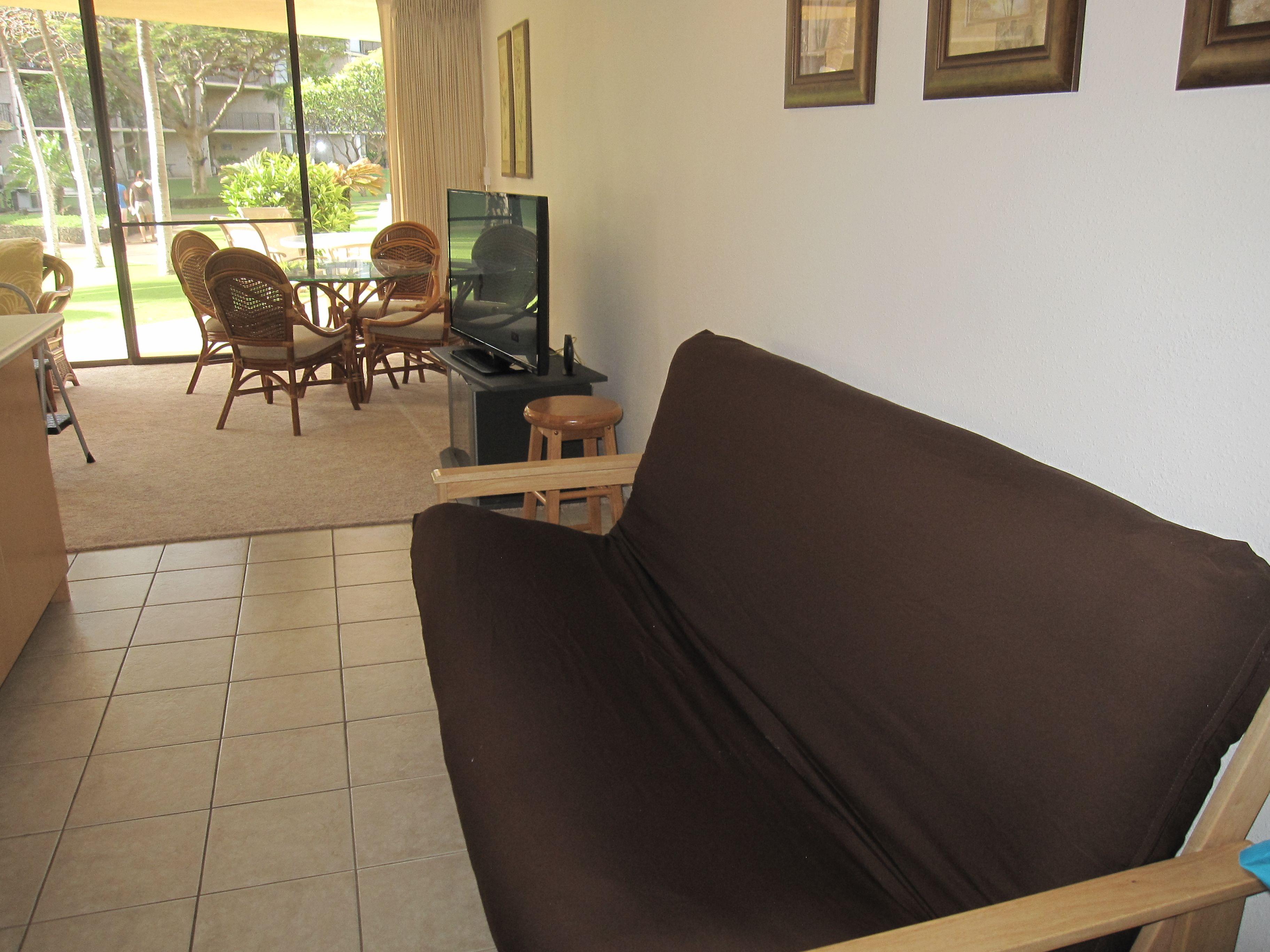 Ein Wohnzimmer mit einem braunen Sofa, einem Fernseher und einem Essbereich mit Stühlen und einem Tisch.