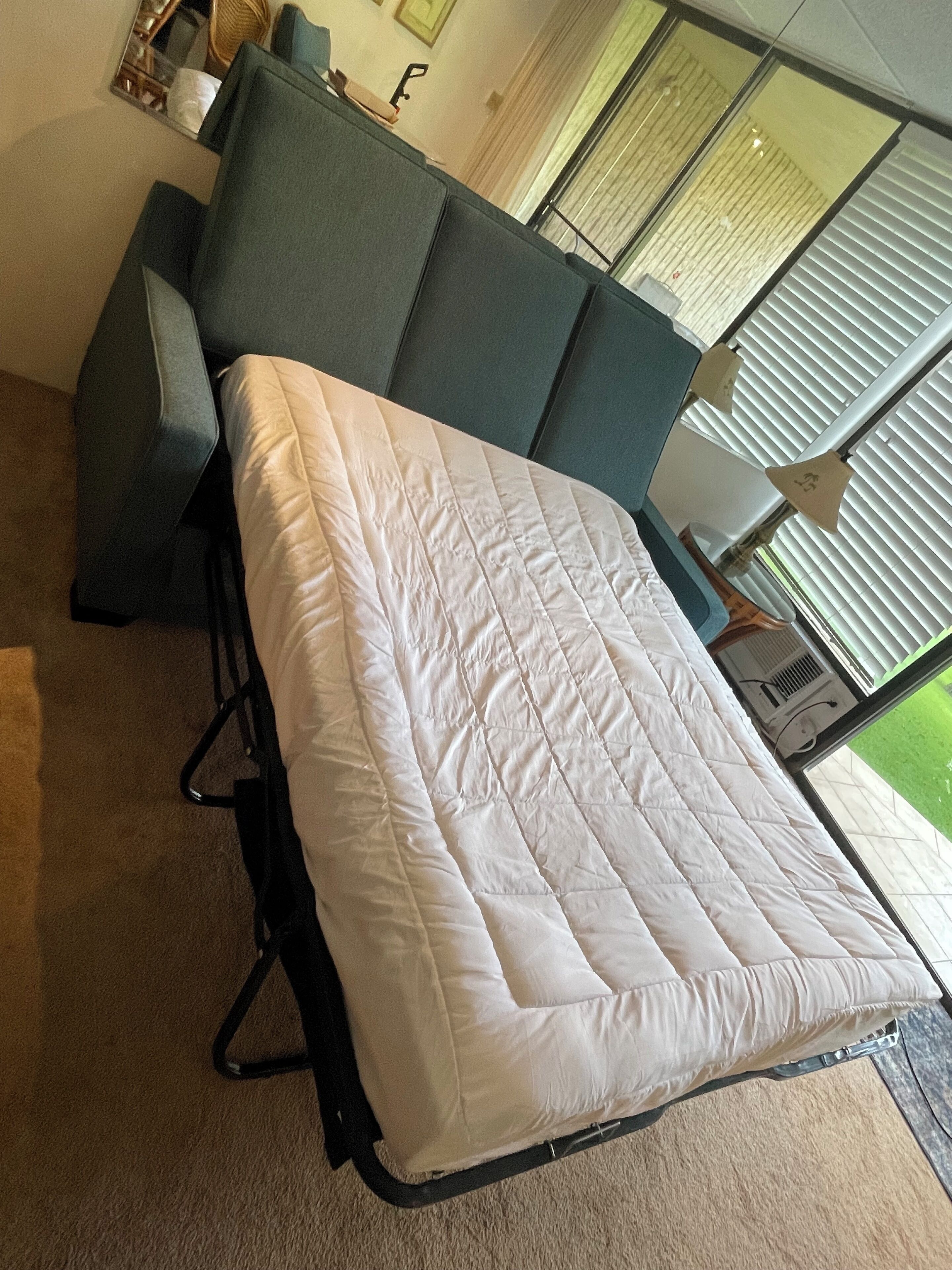 Un lit compact avec une couette blanche, une tête de lit grise et un cadre noir.