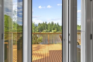 Enjoy a serene lake view from this deck, surrounded by a forested area.