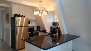 A modern kitchen with stainless steel appliances, a black countertop island, and a chandelier. - Beautiful Mountain Home with Gorgeous View (Franklin)