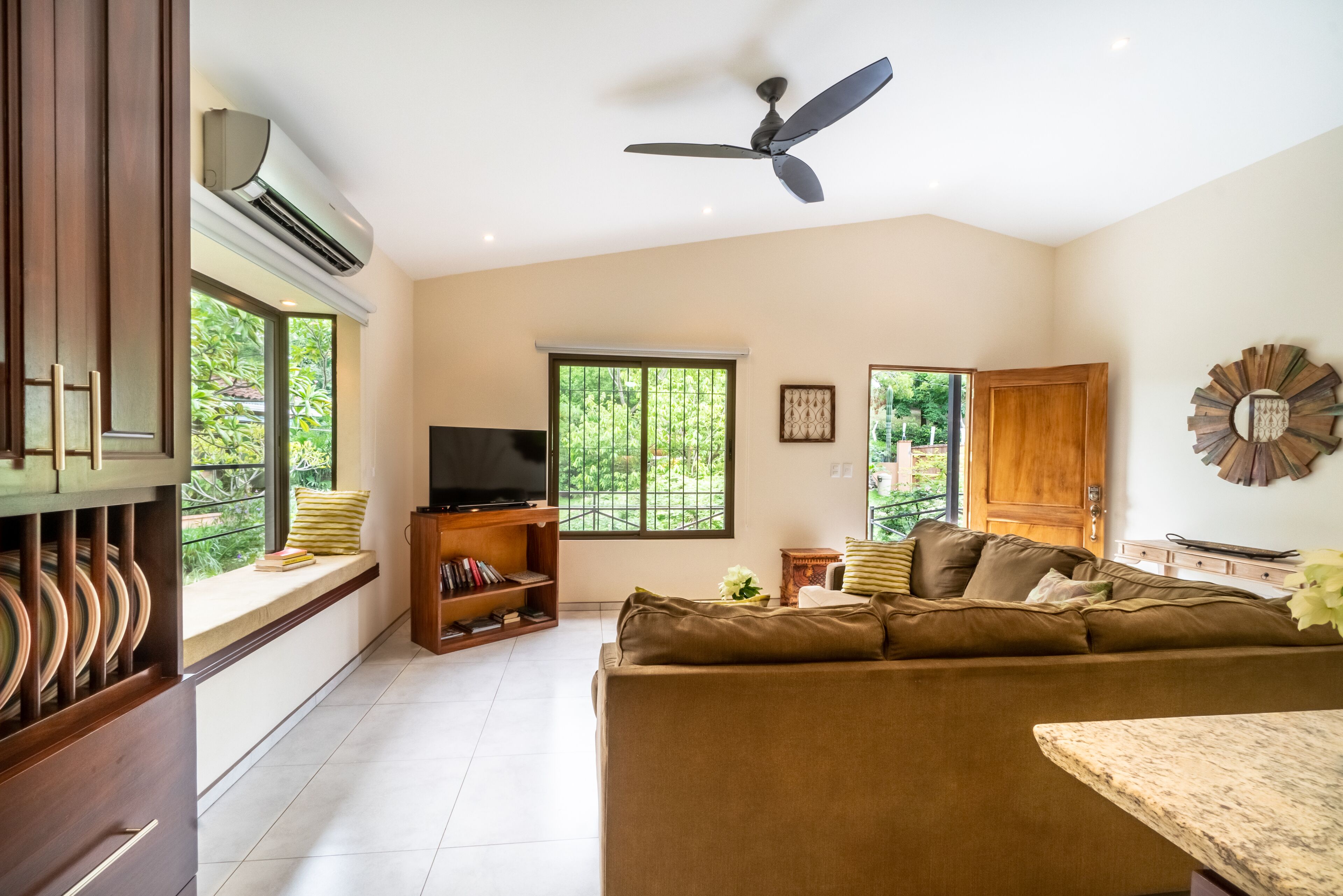 Un salon avec un canapé, un téléviseur et un ventilateur de plafond.