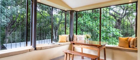 A room with large windows, a wooden bench, and a table.