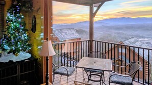 A wooden deck with a table and chairs, a Christmas tree, and a view of mountains. - Romantic Escape with panoramic Mountain Views, great location 2.5 steps to enter (Sevierville)