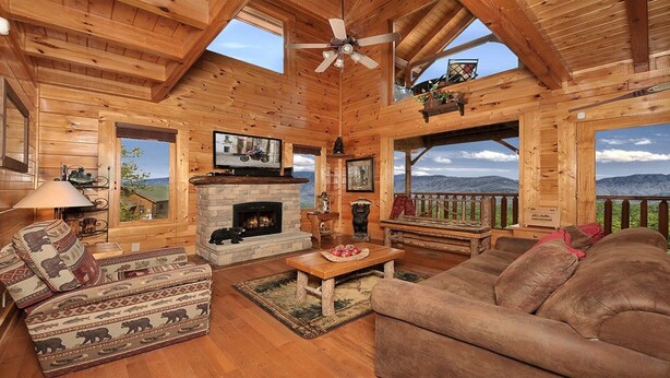 A log cabin interior with a fireplace, wooden furniture, a television, and a balcony with a mountain view. - Romantic Escape with panoramic Mountain Views, great location 2.5 steps to enter (Sevierville)