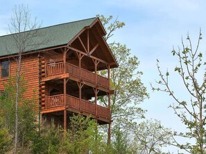 Une cabane en rondins dotée d’un balcon à deux étages et d’un toit végétalisé.