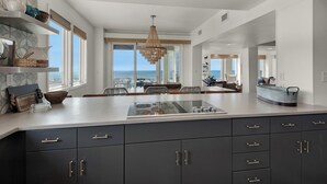 A spacious kitchen with a large island, dark cabinets, and a view of the ocean.