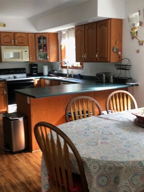 Compact kitchen with microwave, coffee maker, and toaster, featuring a sink and dining area.