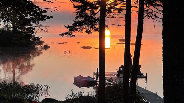 Un cadre idyllique au bord du lac, avec un quai, des chaises et un bateau.