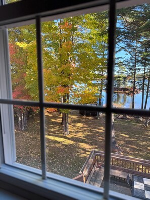A view through a window with a wooden deck and a lake. - Family Friendly Waterfront Escape -7BR w/Dock, Eagle Views, Kayaks & Near Acadia (Penobscot)