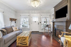 A living room with a sofa, a wooden coffee table, a fireplace, and a chandelier. - Historic Bradshaw House! (Jacksonville)
