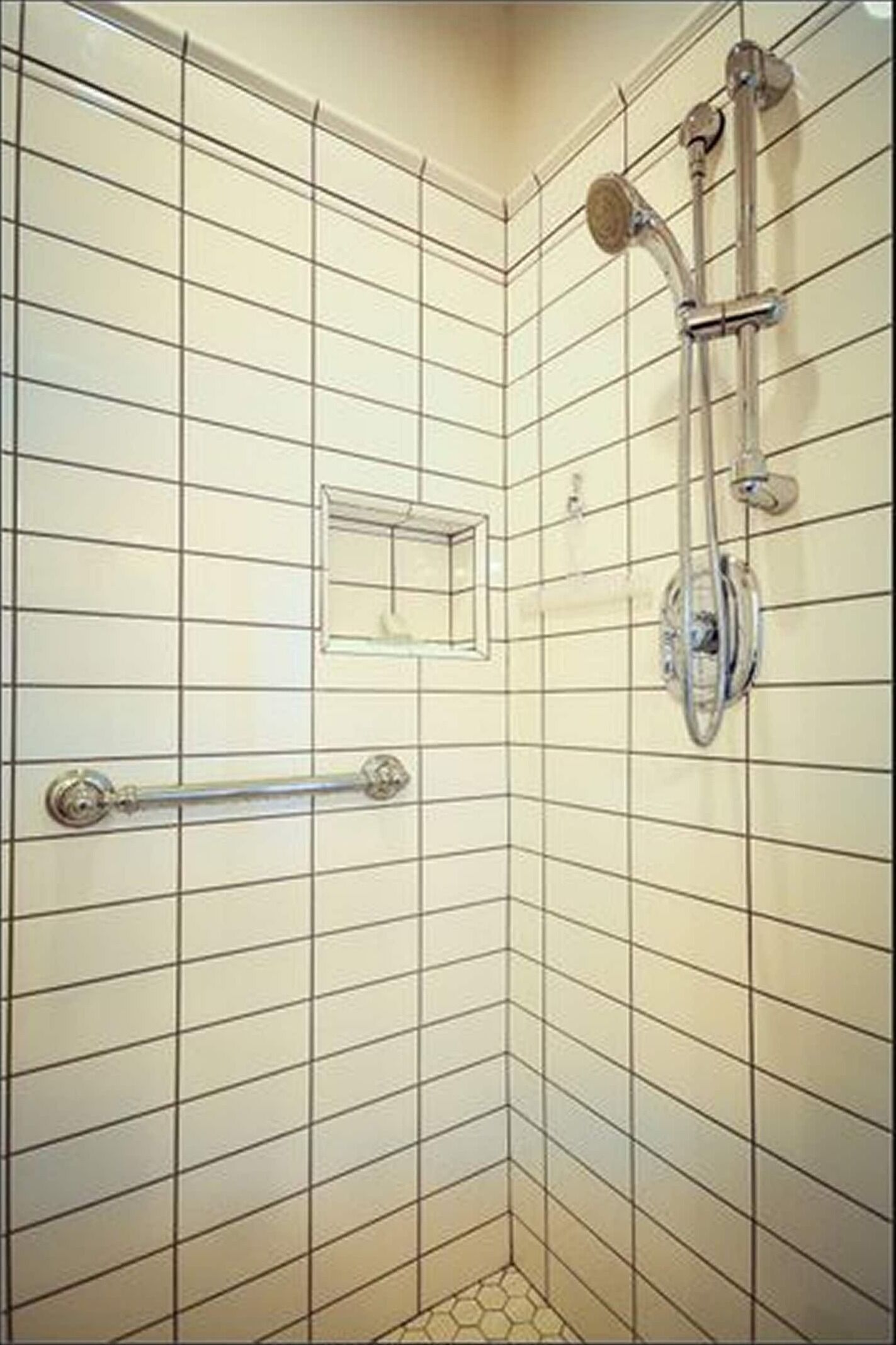 Een douchehoek met een handdouche, een tweede handdouche en een douchekop aan de muur.
