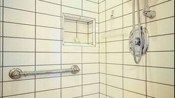 Een douchehoek met een handdouche, een tweede handdouche en een douchekop aan de muur.