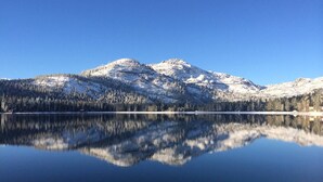 Un lac paisible qui reflète les montagnes enneigées et une forêt dense.