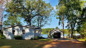 A cabin with a porch and a garage, surrounded by trees and a lake. - Waterfront with Private Pier and Tranquil Water views! (Gloucester Courthouse)
