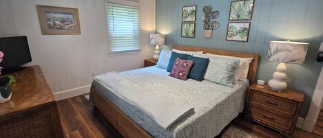 A bedroom with a bed, bedside tables, a television, and wall art.