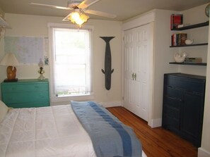 Cozy retreat with a large bed, ceiling fan, and a dresser with mirror.