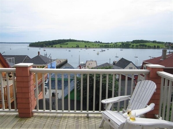 Relax on the balcony with a serene view of the lake, featuring a comfortable Adirondack chair and a small table.