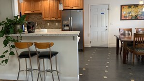 Eine moderne Küche mit Holzausstattung, einem Edelstahlkühlschrank und einer Bar mit Hockern.