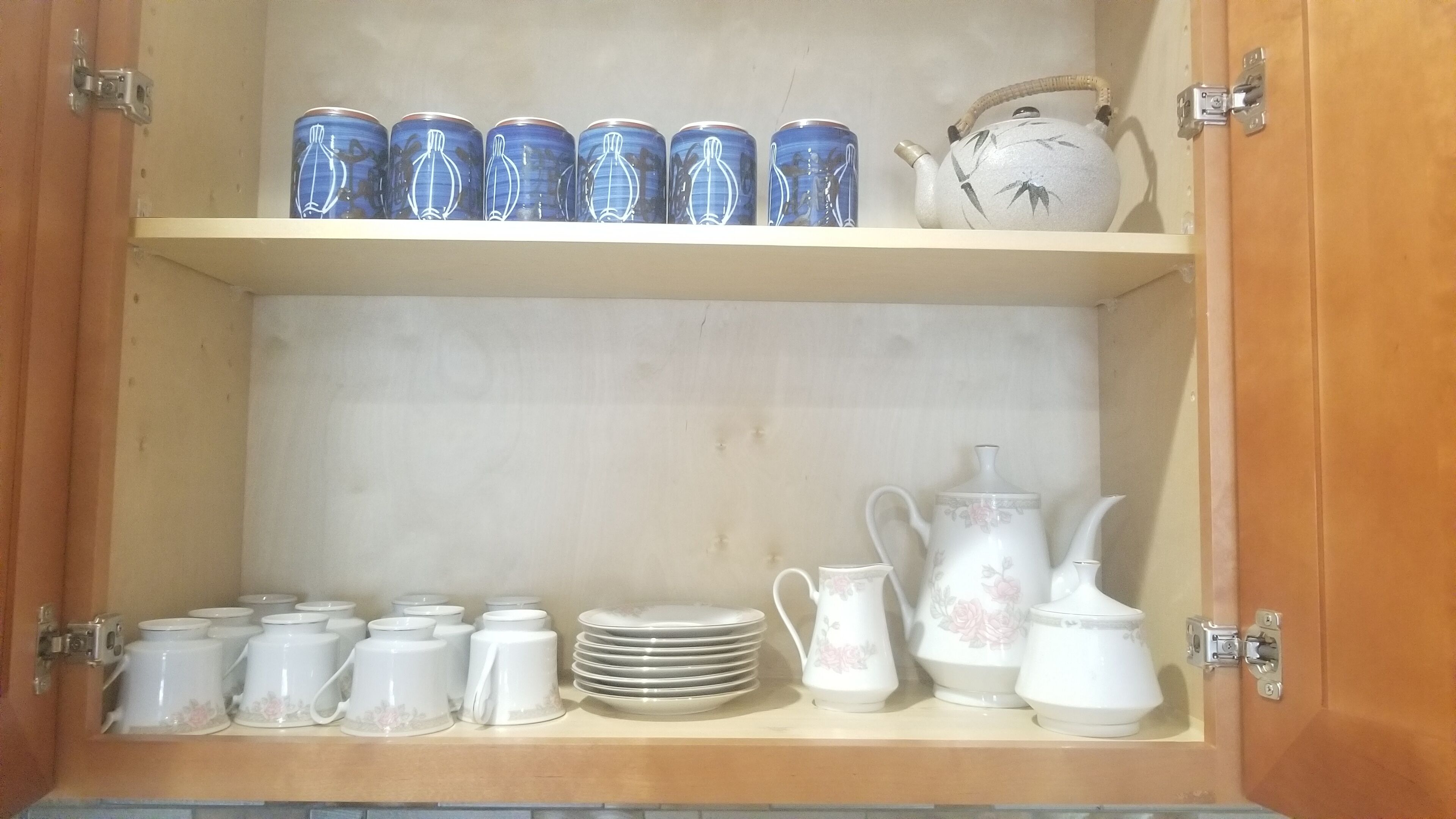 A wooden cabinet with shelves holding various kitchenware items.