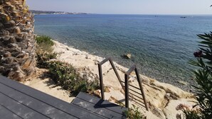 Paesaggio costiero con un pontile di legno, acqua limpida e costa in lontananza.