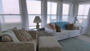 A living room with a beige sofa, a matching ottoman, a blue accent sofa, and a small side table with a lamp and books. - Quiet North Beach Oceanfront Steps to Private Beach  3 Night Min Stays Available (North Beach)