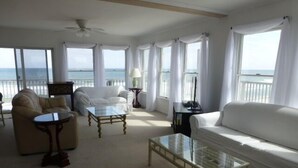 A spacious living room with a white sofa, two armchairs, and a coffee table. Large windows offer a view of the ocean. - Quiet North Beach Oceanfront Steps to Private Beach  3 Night Min Stays Available (North Beach)