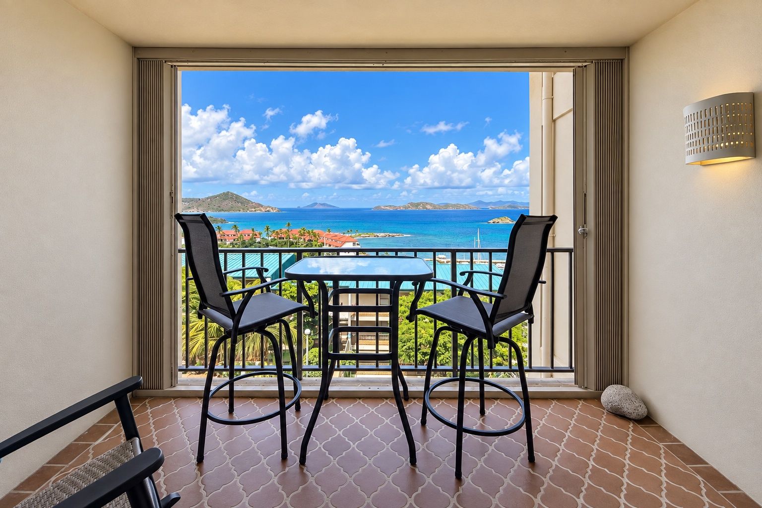 Ein Balkon mit Tisch und Stühlen, Blick aufs Meer und ein klarer Himmel.