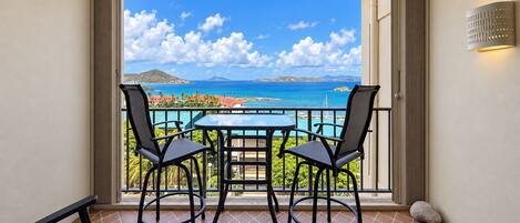 Un balcon avec une table et des chaises, une vue sur l’océan et un ciel dégagé.