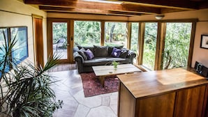 A modern living room with a sofa, coffee table, and large windows overlooking a garden. - Oasis Retreat Nestled Near World Renown Hiking (Sedona)