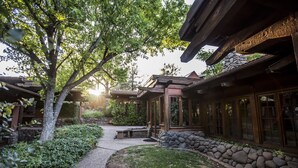 A traditional-style building with a stone pathway leading to a wooden deck, surrounded by lush greenery and a stone wall. - Oasis Retreat Nestled Near World Renown Hiking (Sedona)