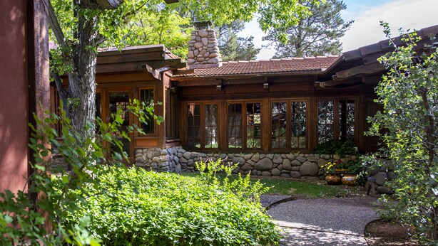 A rustic cabin with a stone chimney, large windows, and a well-maintained garden. - Oasis Retreat Nestled Near World Renown Hiking (Sedona)